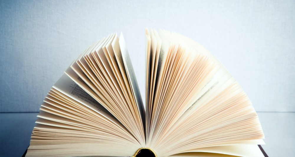 Fanned book on a white reflective surface